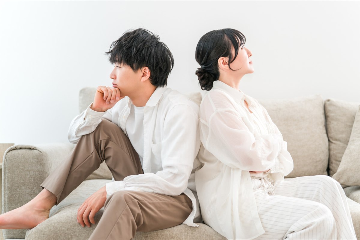 ソファで背中合わせに座り、それぞれ別の方向を見ているふたり