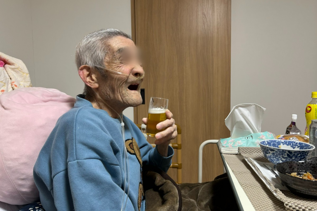 亡くなる1か月前、主治医の許可を得て在宅酸素をしながら大好きなビールを飲み、笑顔を見せる義父