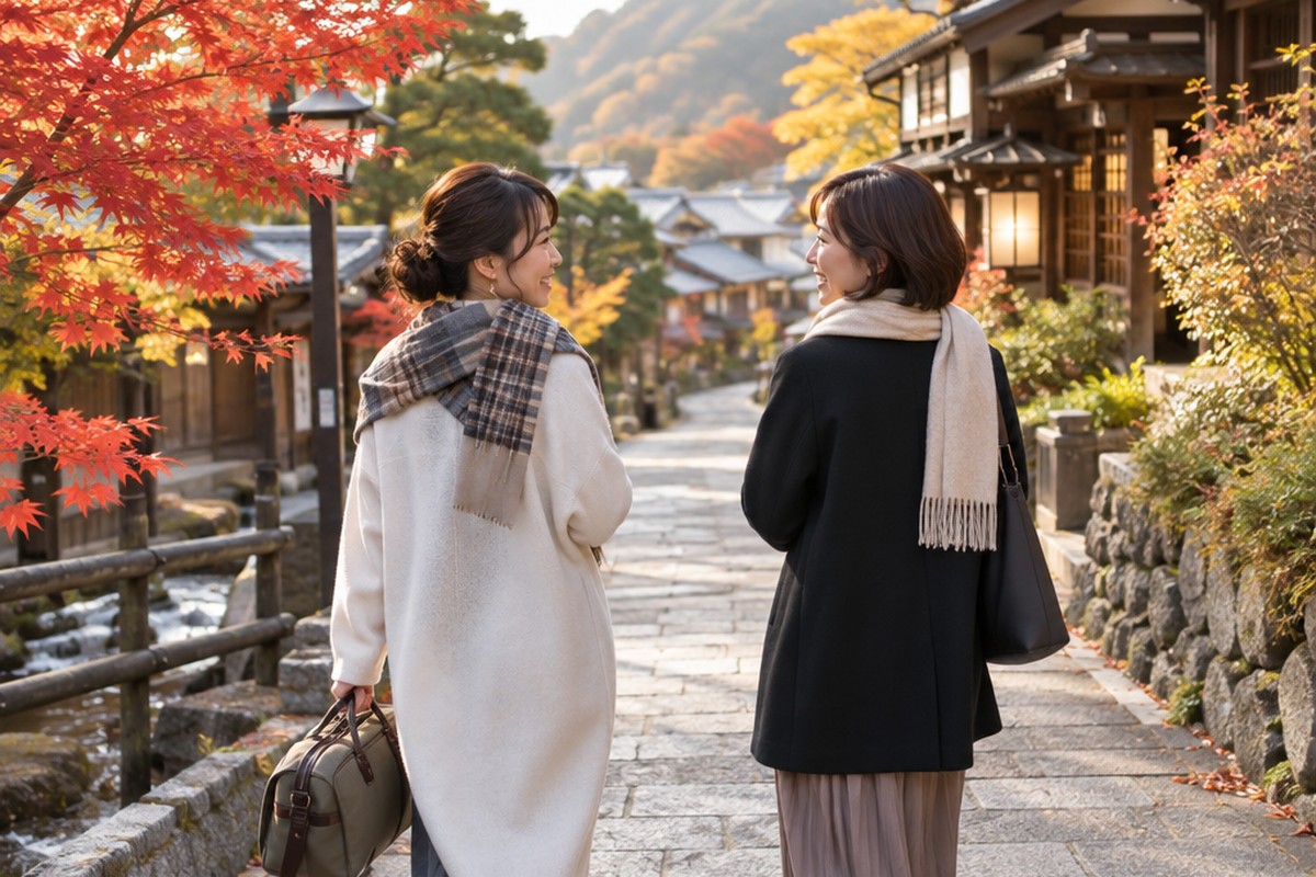 紅葉の温泉街を、笑顔で話しながら並んで歩く女性ふたり