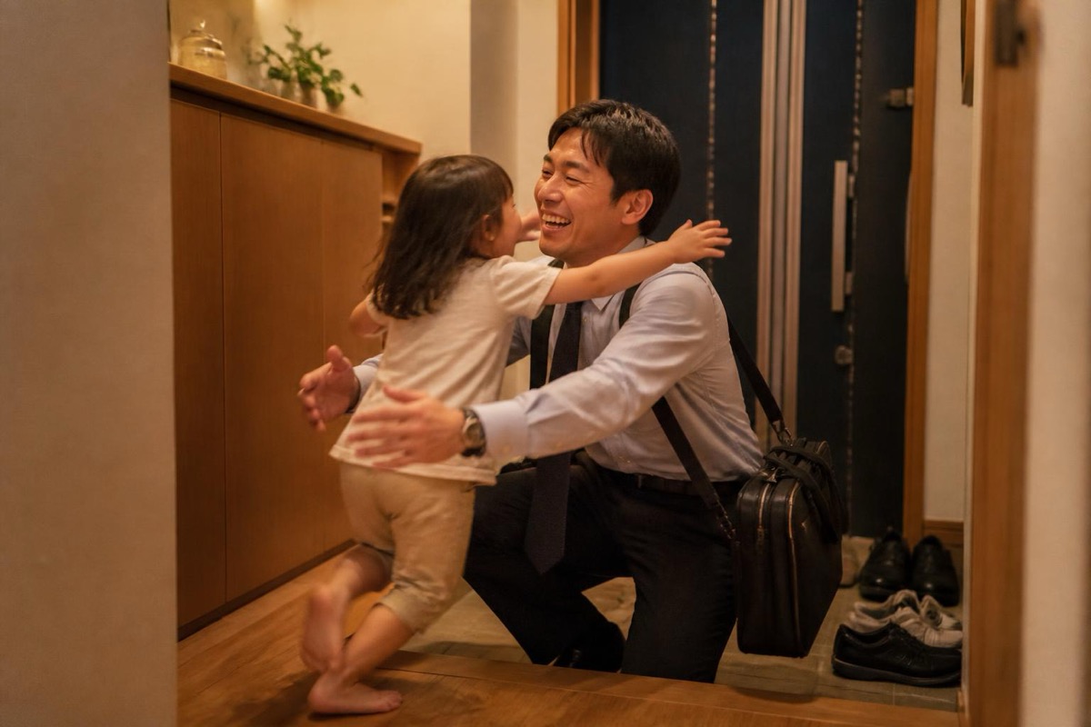 仕事から帰った父親に玄関で駆け寄って抱きつく幼い娘